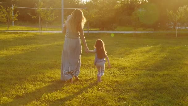 若い母親が公園を散歩して夕日 — ストック動画