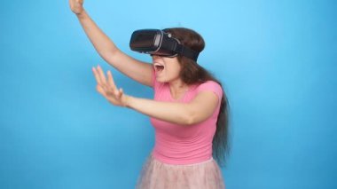 Mutlu genç kadın mavi arka plan üzerinde bir sanal gerçeklik kulaklık kullanarak