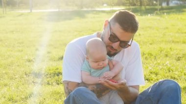 Baba ve oğul birlikte çimlere oturup akşam günbatımı yaz