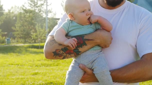 Un hombre sostiene a su hijo en brazos al aire libre. — Vídeos de Stock