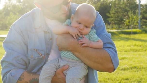 A man is holding his son in his arms outdoors — Stock Video