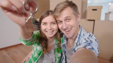 Yeni ev ve selfie anahtarları gösterilen Çift