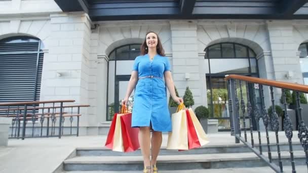 Jeune femme heureuse avec des sacs à provisions marchant hors du magasin — Video