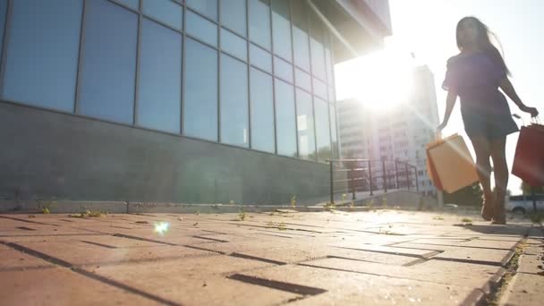 Ung kvinna som bär kassar medan promenader längs gatan — Stockvideo