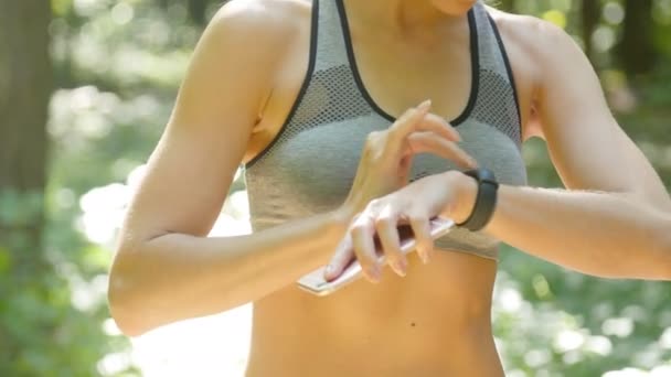 Una mujer mira un rastreador de fitness durante un entrenamiento — Vídeos de Stock
