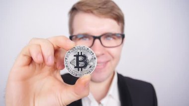 Bir madeni para bitcoin olan genç bir adam