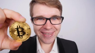 Bir madeni para bitcoin olan genç bir adam