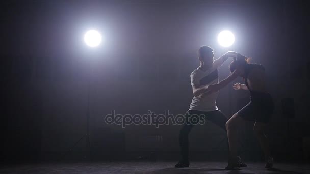 Pareja bailando en una habitación oscura en la contraluz — Vídeo de stock