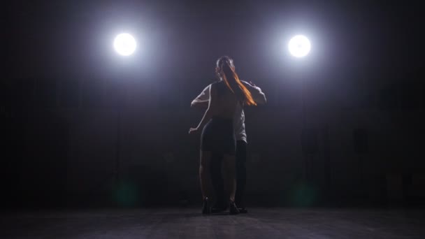 Par som dansar i ett mörkt rum i motljuset — Stockvideo