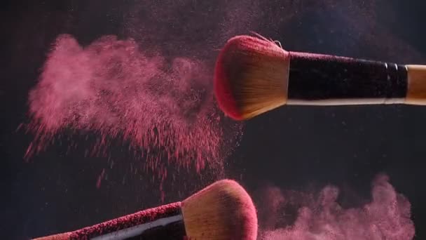 Dos pinceles de maquillaje con polvo sobre un fondo oscuro — Vídeos de Stock