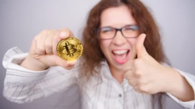 Bir altın Bitcoin para tutan kadın