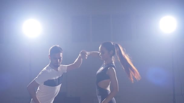 Молодая пара танцует в темной комнате с дымом — стоковое видео