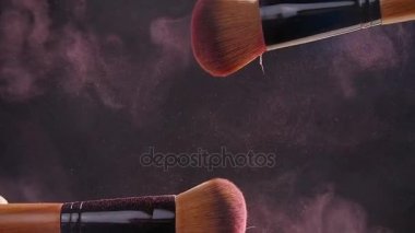 Karanlık bir arka plan üzerinde tozu ile iki makyaj fırçaları
