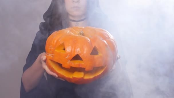 Žena čarodějnice stojí s dýně v kouři