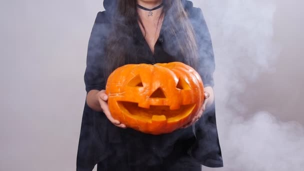 Mujer bruja está de pie con la calabaza en el humo — Vídeo de stock