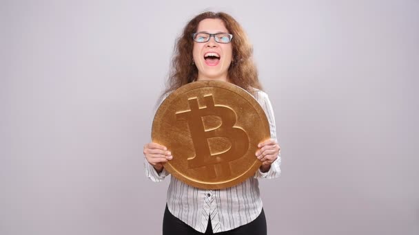 Lycklig kvinna håller en gyllene Bitcoin — Stockvideo