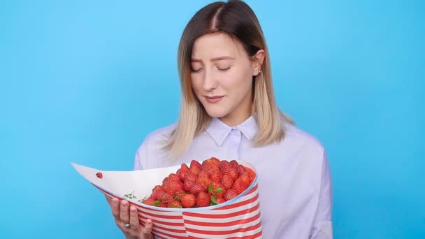 Een leuke jonge vrouw met een boeket van aardbeien — Stockvideo