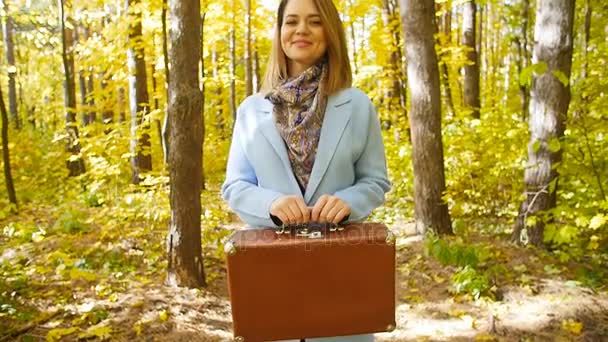 Junge Frau mit Koffer in einem Park im Herbst — Stockvideo