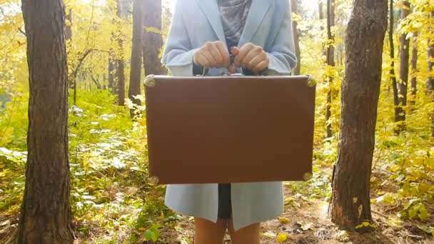 Ung kvinna med en resväska i en park på hösten — Stockvideo