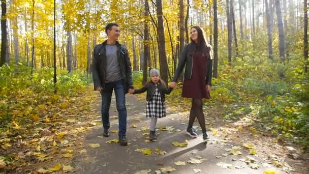 Família feliz com uma pequena filha caminhar no parque de outono — Vídeo de Stock