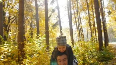 Baba ve küçük kızı sonbahar parkta eğleniyor