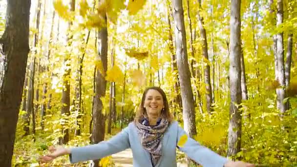 Νέοι ευτυχισμένη γυναίκα ρίχνει φύλλα του φθινοπώρου — Αρχείο Βίντεο