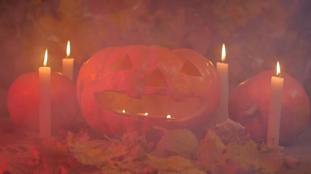 Halloween-Kürbis und Kerzen auf Blättern und Rauch — Stockvideo