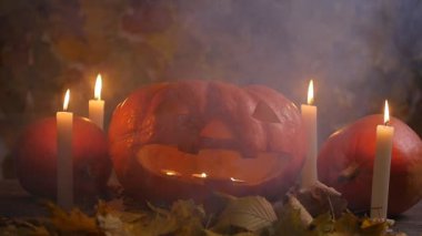 Cadılar Bayramı Balkabağı yüzünde ahşap arka plan ve sonbahar yaprakları