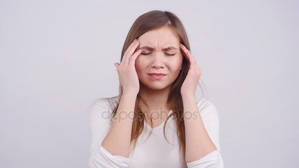 Жінка з головним болем тримає голову на білому тлі — стокове відео