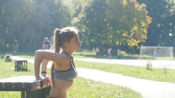 Молодая женщина отжимается в летнем парке — стоковое видео