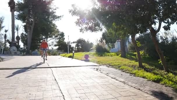 Jovem numa bicicleta na cidade ao pôr-do-sol no verão — Vídeo de Stock