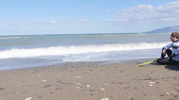 Молодой человек с каяком на берегу моря — стоковое видео