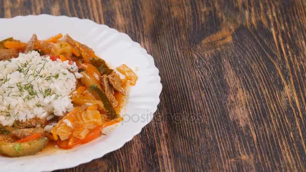 Рис с мясом и овощами на деревянном столе — стоковое видео