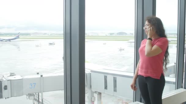 MOSCÚ, RUSIA - 25 DE MAYO DE 2017. Mujer hablando por teléfono en el aeropuerto cerca de la ventana — Vídeo de stock