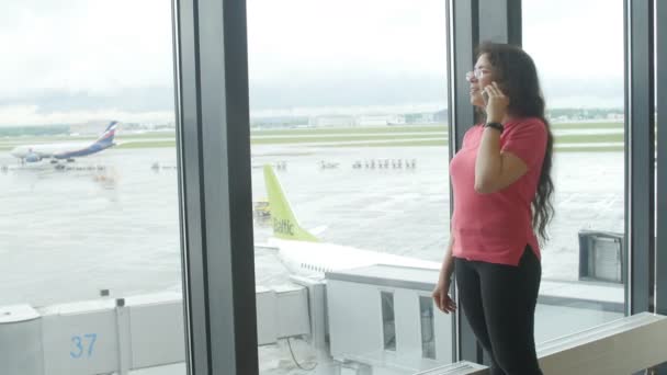 MOSCOW, RUSSIA - MAY 25, 2017. Woman talking on the phone at the airport near the window — Stock Video