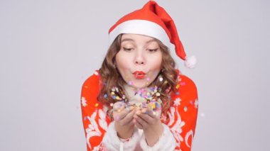Uzak konfeti üfleme Santas şapka giyen genç kadın