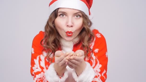 Mujer joven con sombrero de Santas soplando confeti — Vídeo de stock