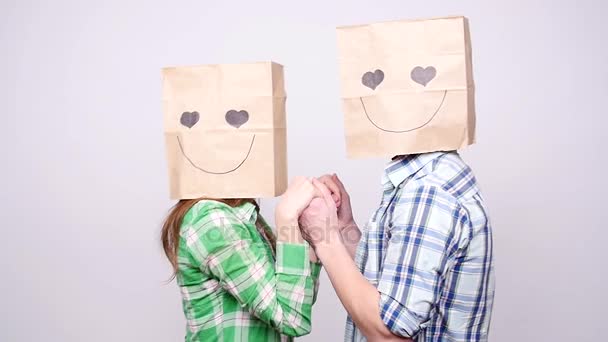 Young couple in love with bags over heads on gray background — Stock Video