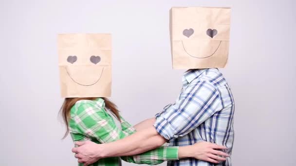 Young couple in love with bags over heads on gray background — Stock Video