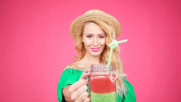 Νεαρή γυναίκα χέρι που κρατά το smoothie κούνημα ροζ τοίχο — Αρχείο Βίντεο