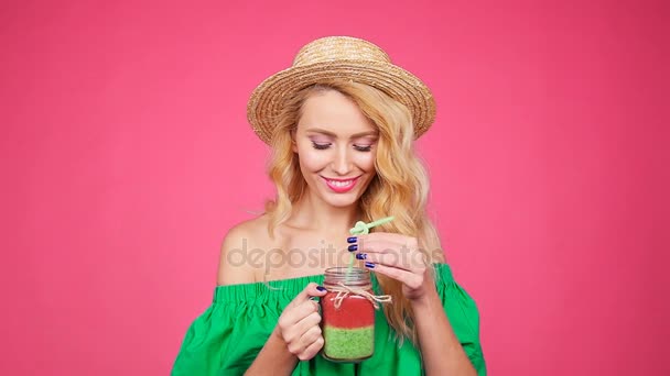 Joven mano sosteniendo batido batido contra la pared rosa — Vídeos de Stock