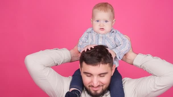 Pai com pequeno filho bonito sobre fundo rosa — Vídeo de Stock