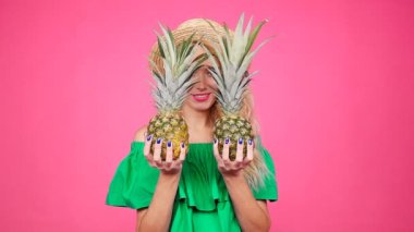 Genç kadın bir ananas tutan bir pembe şapkalı