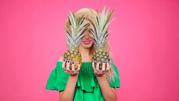 Jeune femme au chapeau tenant un ananas sur un fond rose — Video