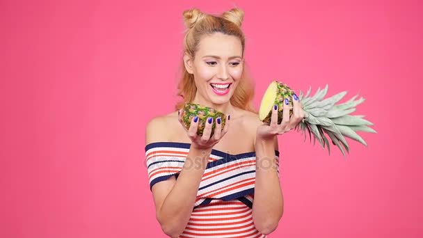 ピンクの背景のパイナップルを保持している若い女性 — ストック動画