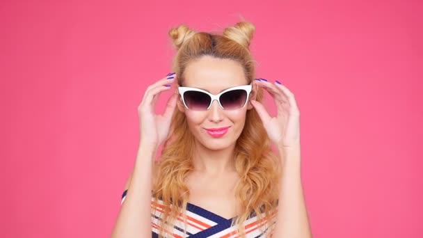 Mujer joven sobre fondo rosa con gafas de sol — Vídeos de Stock