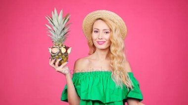 Kadın portre ve ananas pembe bir arka plan üzerinde güneş gözlüğü ile