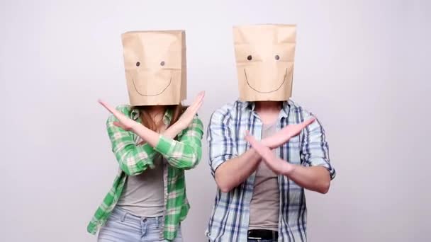 Un jeune couple avec des sacs en papier sur la tête est heureux et danse — Video