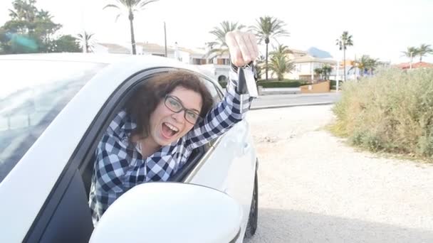 Счастливая женщина показывает ключ от нового автомобиля на открытом воздухе — стоковое видео