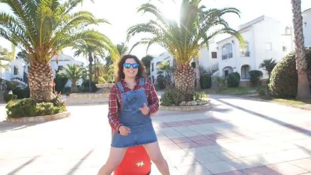 Zomer levensstijl portret van de jonge vrouw poseren met koffer in de buurt van resort — Stockvideo